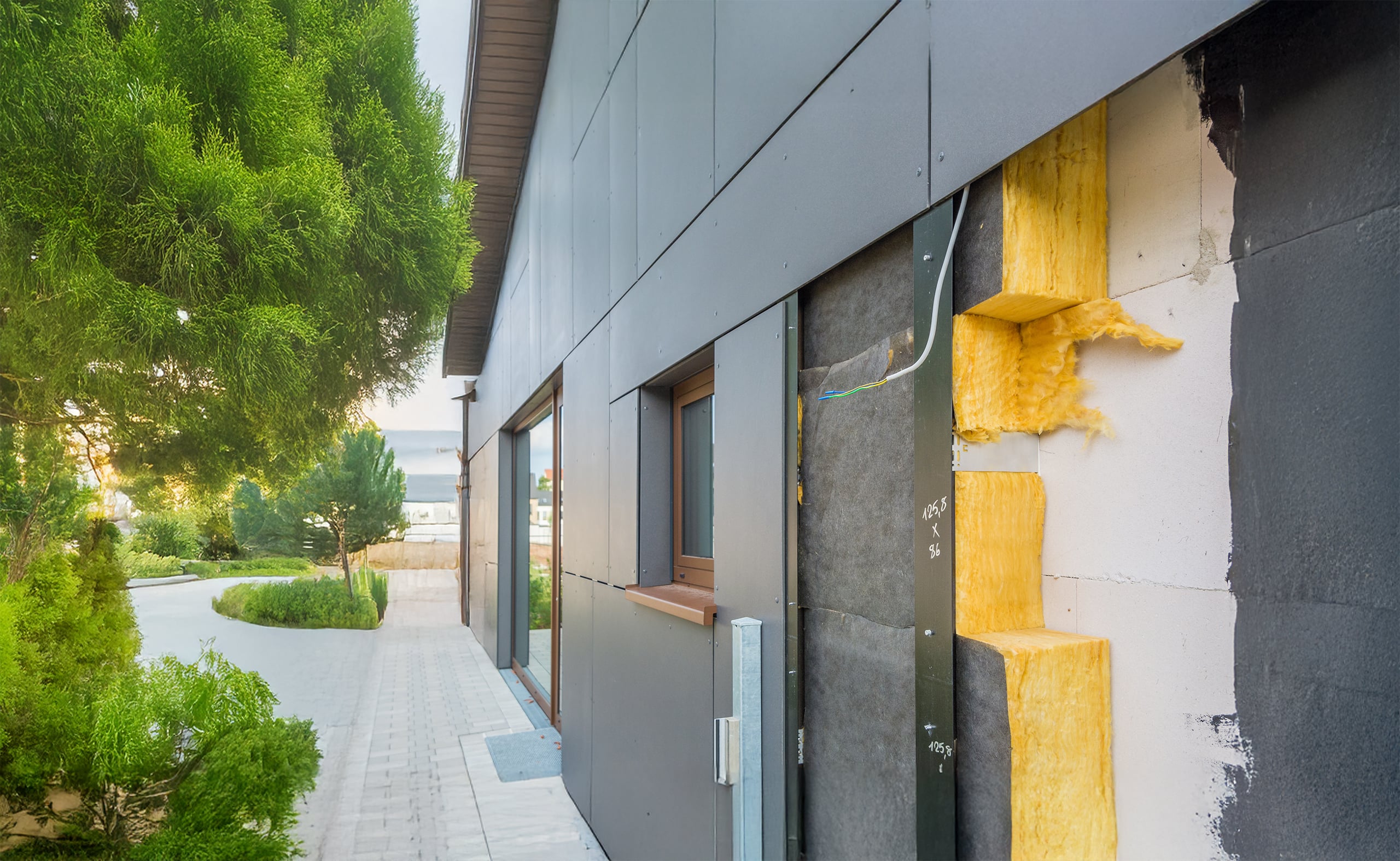 Detailfoto einer modernen Hausfassade mit Fassadenplatten, hinter der die einzelnen Schichten der Wärmedämmung mit Steinwolle gut erkennbar ist.