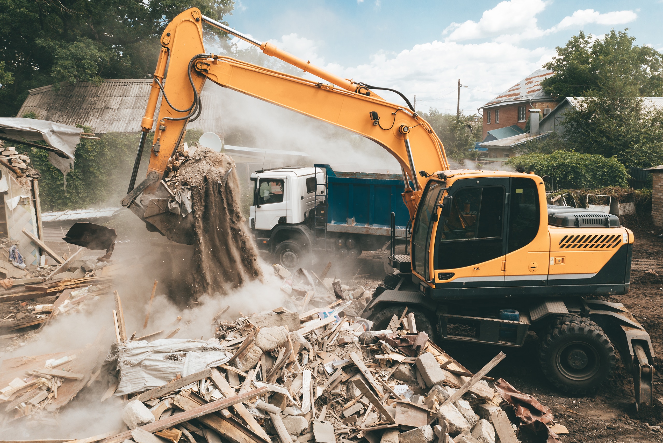 Bagger lädt Bauschutt zum Abtransport in einen LKW. Abriss eines Hauses. Gebäudezerstörung. Aufräumarbeiten für Bebauung und Neubauten.