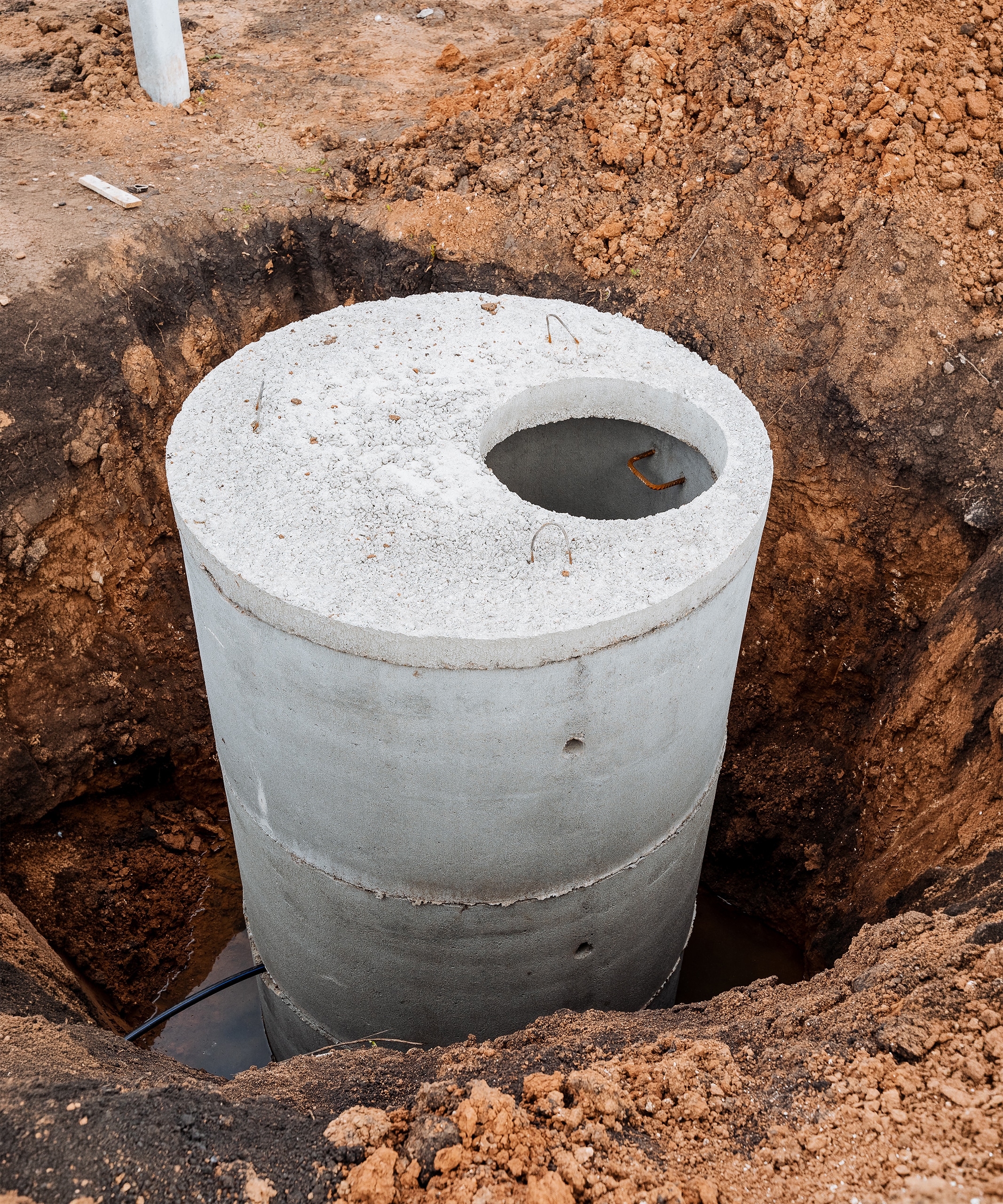 Einbau von Betonringen für die Abwasserleitung im Vorortbereich, Installation einer häuslichen Kläranlage (Senkrgrube) sowie eines runden, in einer Baugrube versenkten Klärbehälters.