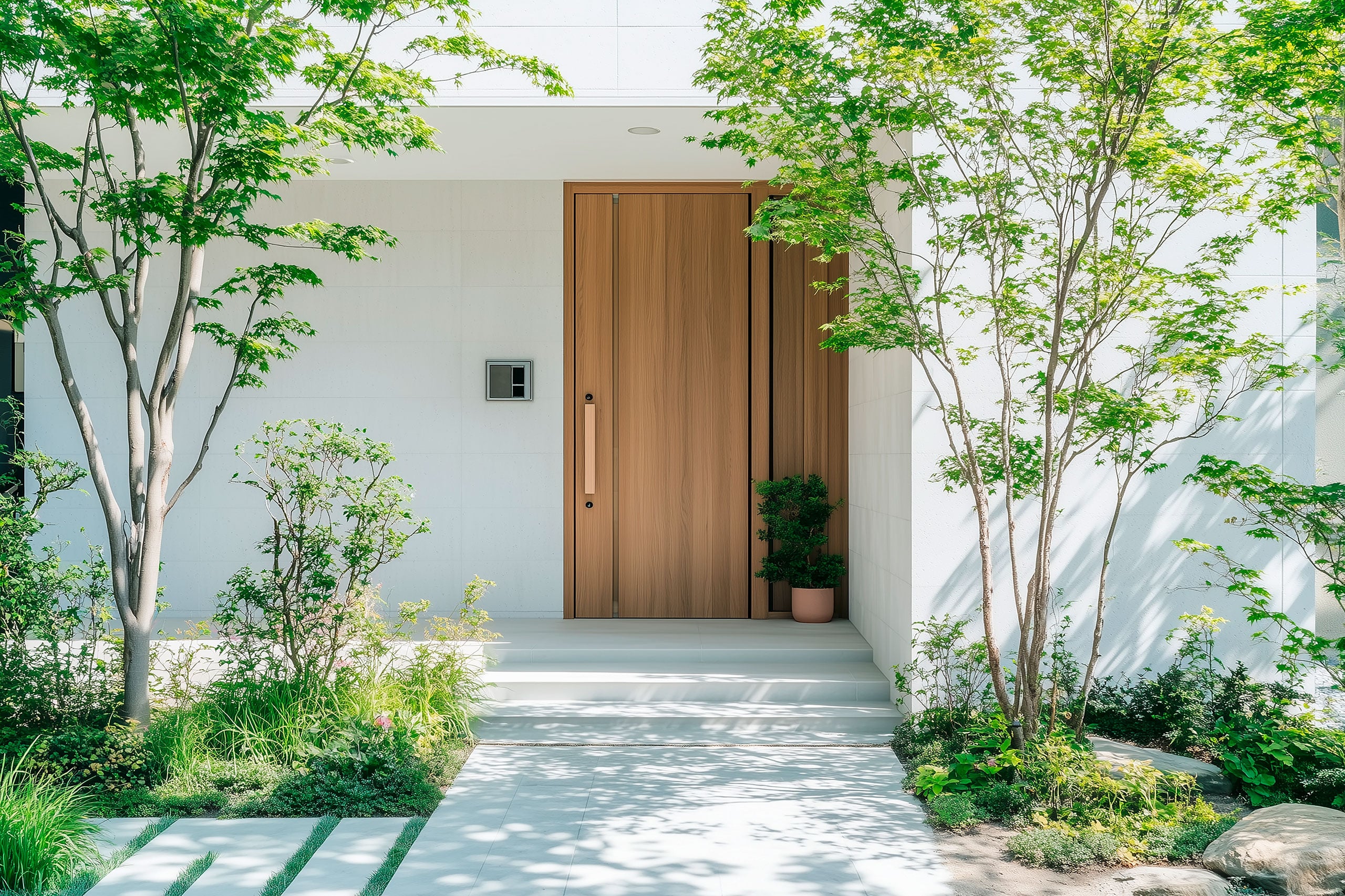 Extravaganter Eingangsbereich eines modernen Wohnhauses mit weißen Fassadenplatten und eindrucksvoller Haustüre aus Massivholz.