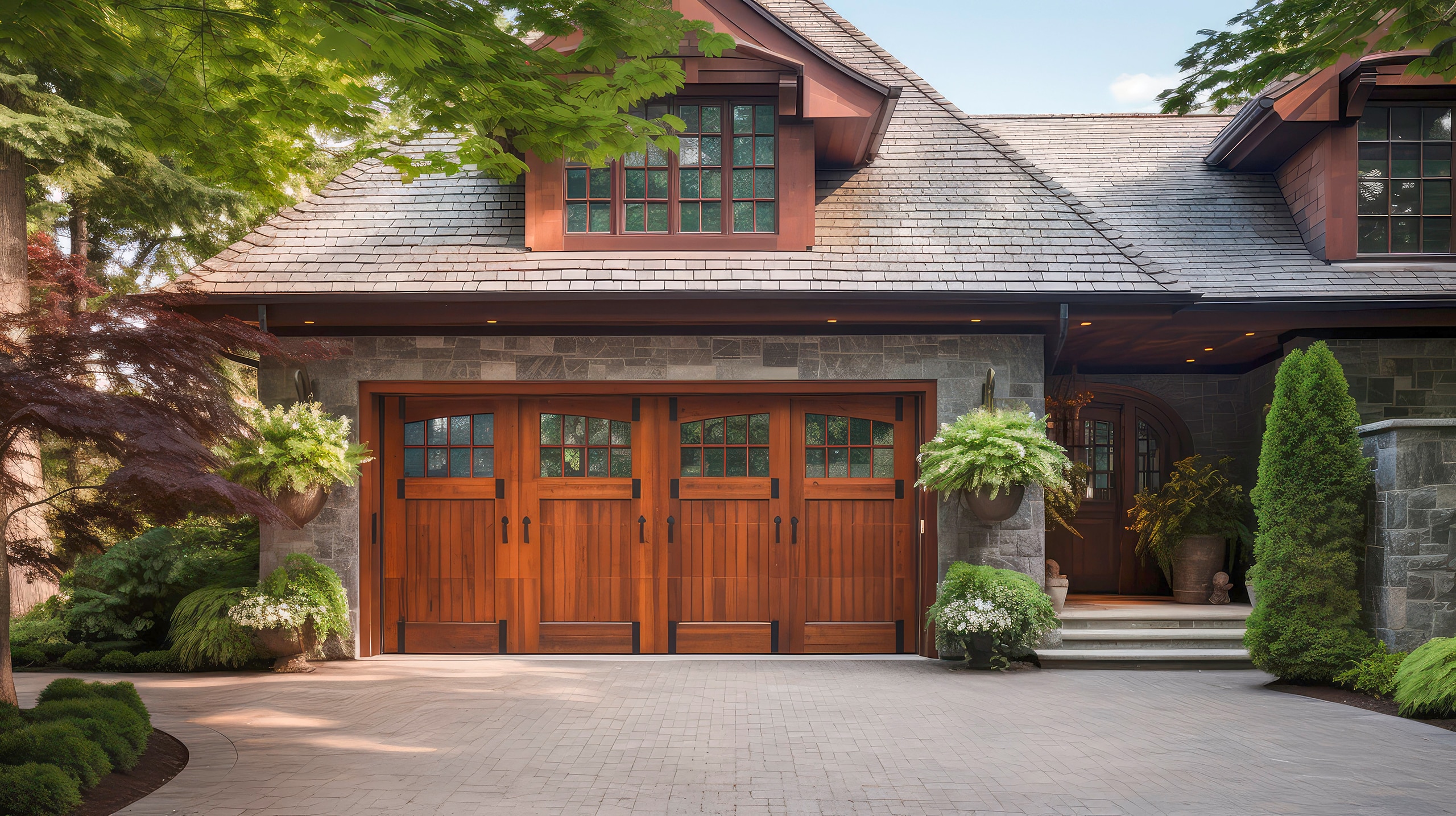 Luxuriöses Landhaus mit Schindeldach und einer großzügigen Doppelgarage mit Flügeltüren aus edlem Holz und schwarzen Metallelementen.