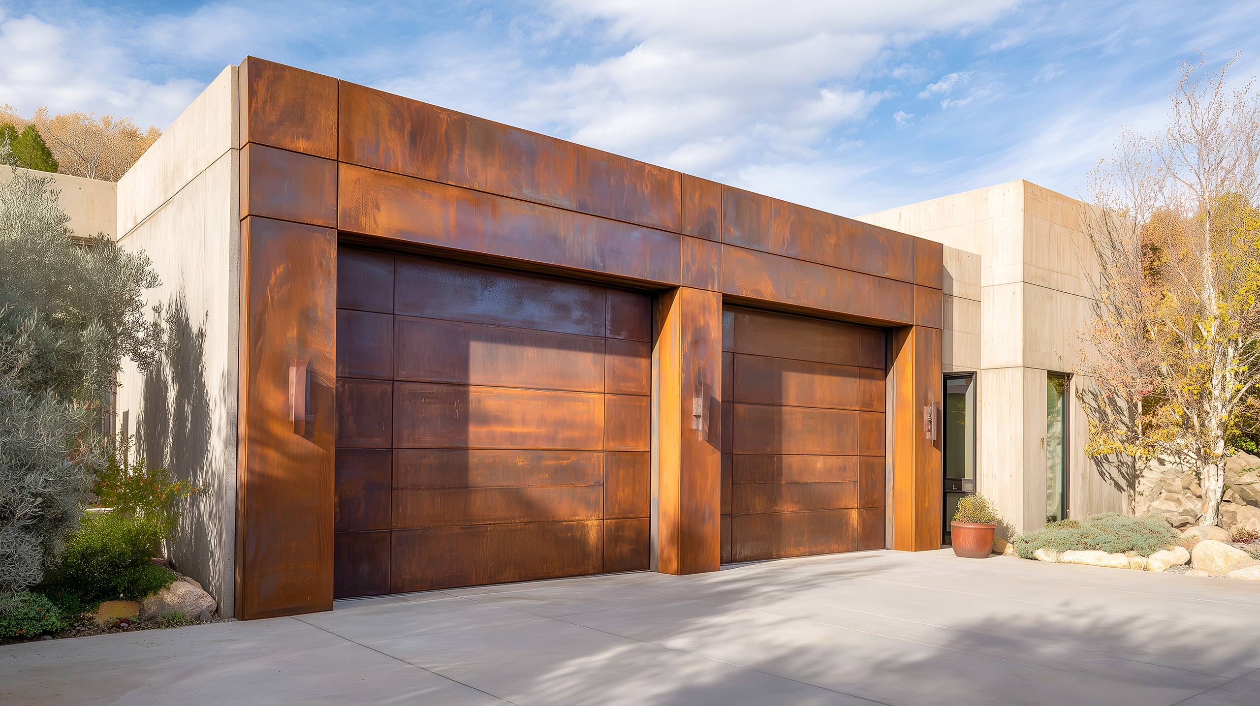 Moderne Betongarage mit Fassaden und Garagentor-Elementen aus Kupfer. Die Doppelagarage mit zwei separaten Decken-Sektionaltoren harmonieren perfekt mit dem Wohngebäude aus Beton.