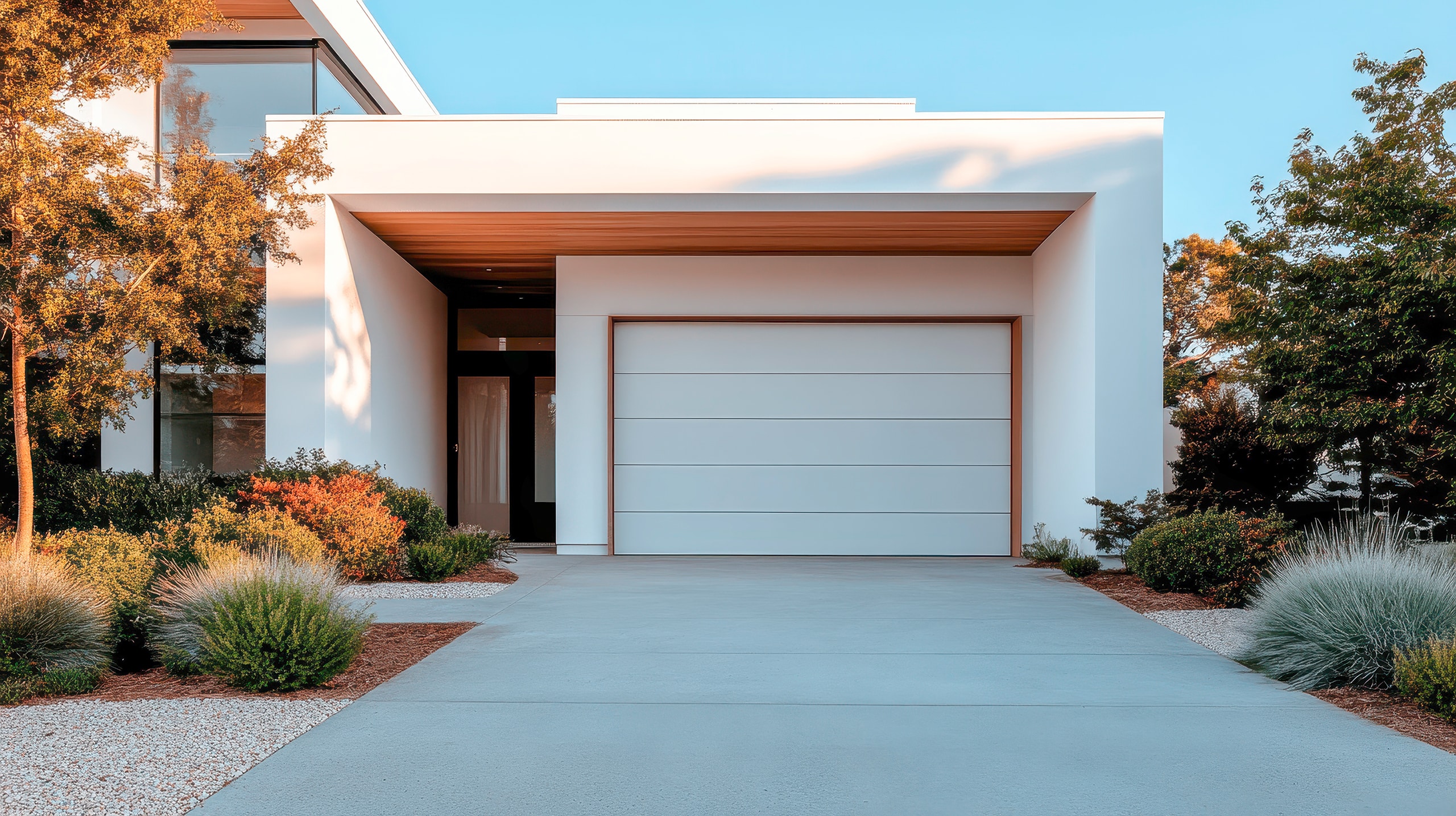 Stilvolles, modernes, weißes Haus mit passendem Garagentor und einem sorgfältig gepflegten Garten, das zeitgenössisches Wohndesign.