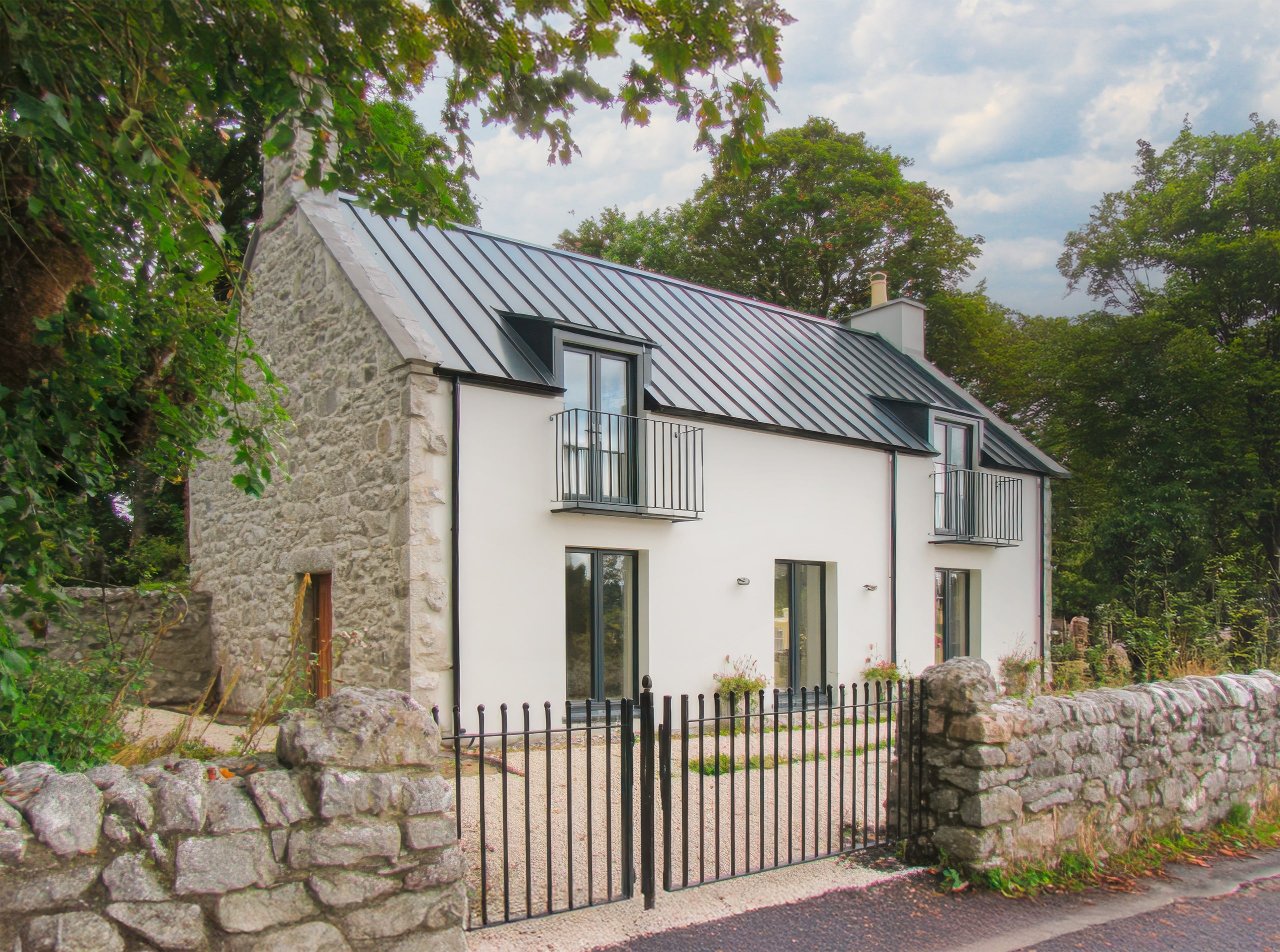 Modernes Steinhaus eingebettet in einer friedlichen ländlichen Umgebung, umgeben von üppigem Grün und an einer ruhigen Straße gelegen.