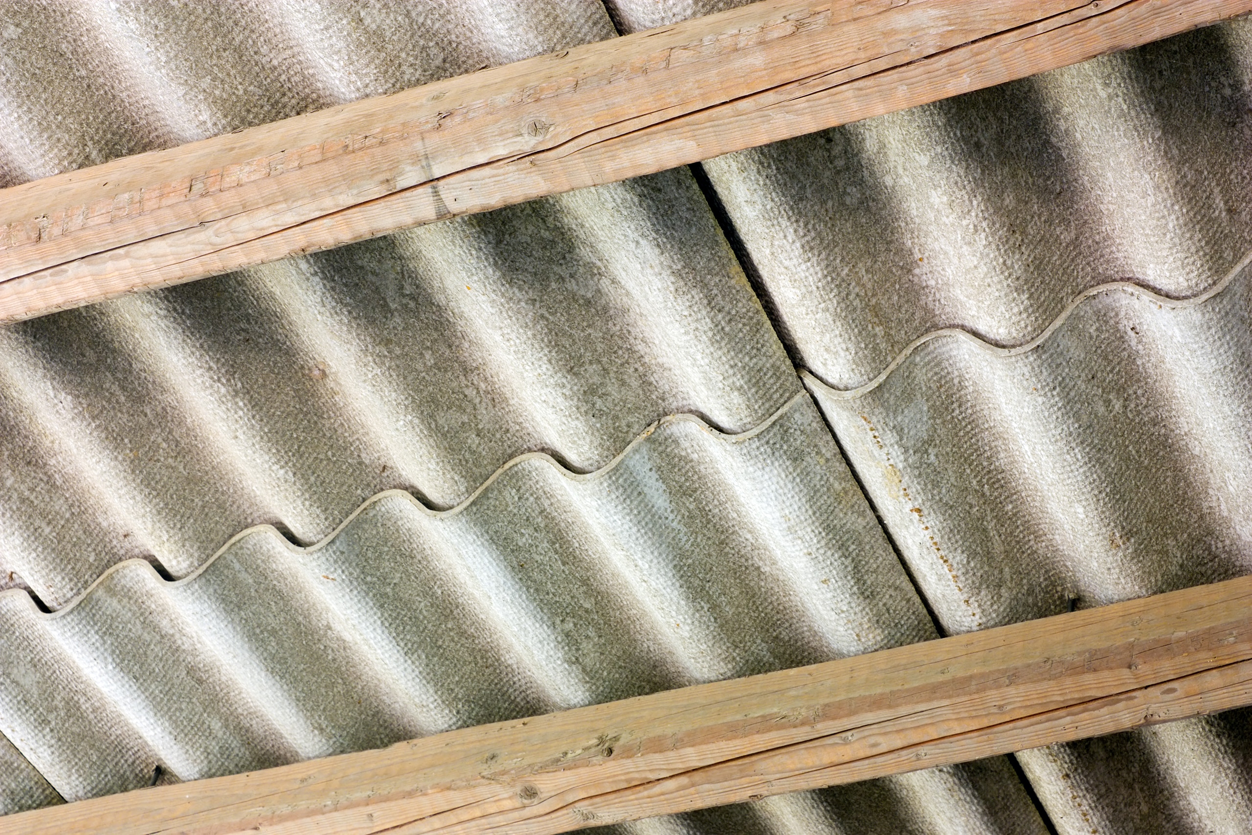 Detailaufnahme von Faserzementplatten als Dacheindeckung, die auf den Holzsparren des Dachstuhles installiert sind.