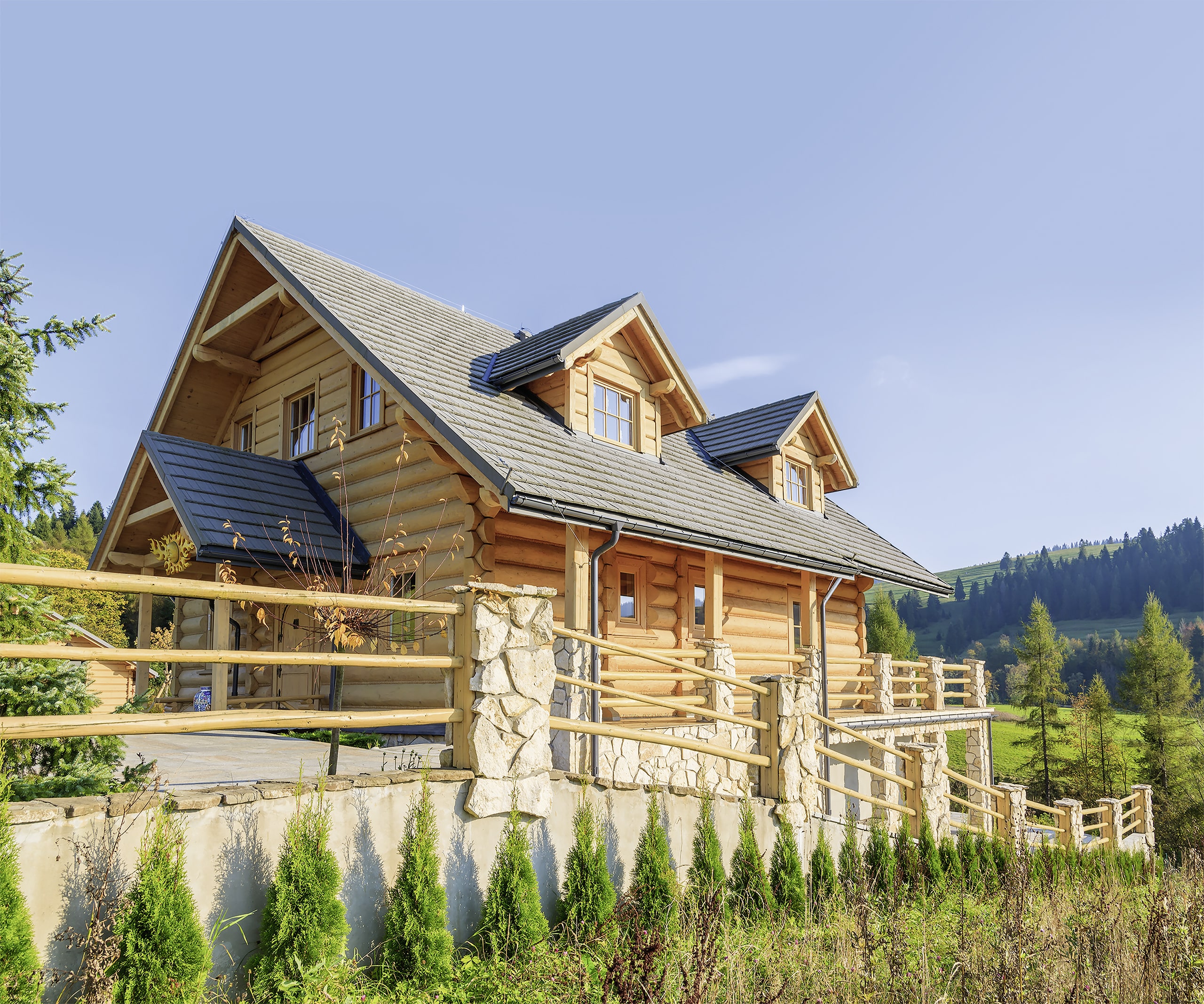 Traditionelles Holzblockhaus aus naturbelassenen Rundholzbohlen mitten in der Natur mit Blick auf Wiesen und Wälder.