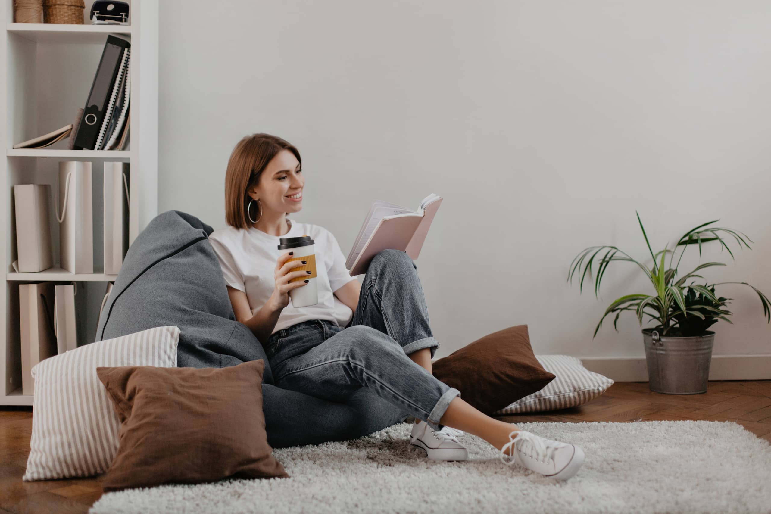Junge Frau, die es sich auf einem Sitzsack bequem macht und ein Buch liest.