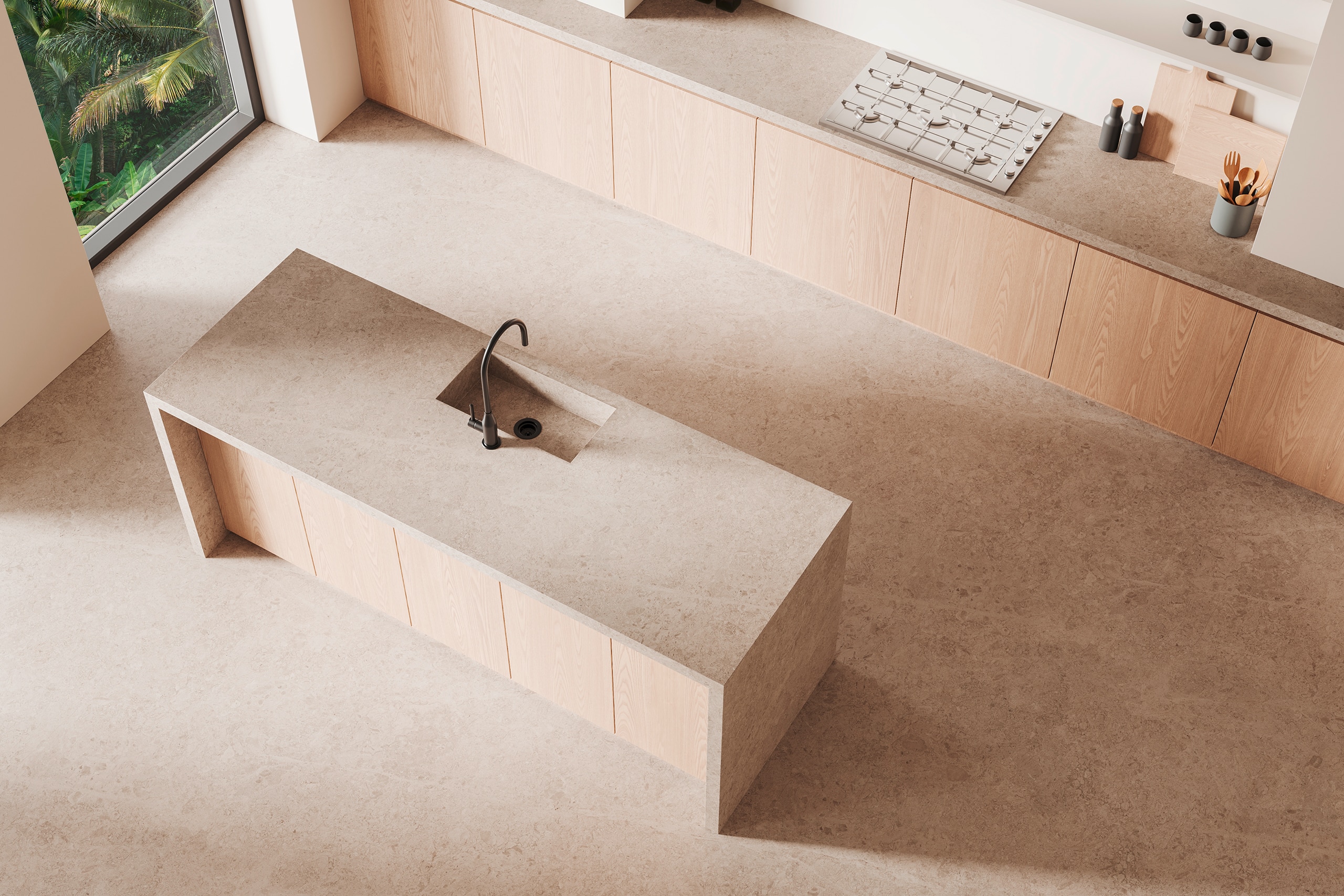 Minimalistisches Kücheninterieur mit beigefarbenen Arbeitsplatten aus Naturstein und dem Bodenbelag aus dem selben Material, einer zentralen Kochinsel mit dunklem, matten Wasserhahn bzw. Armatur und natürlichem Licht.