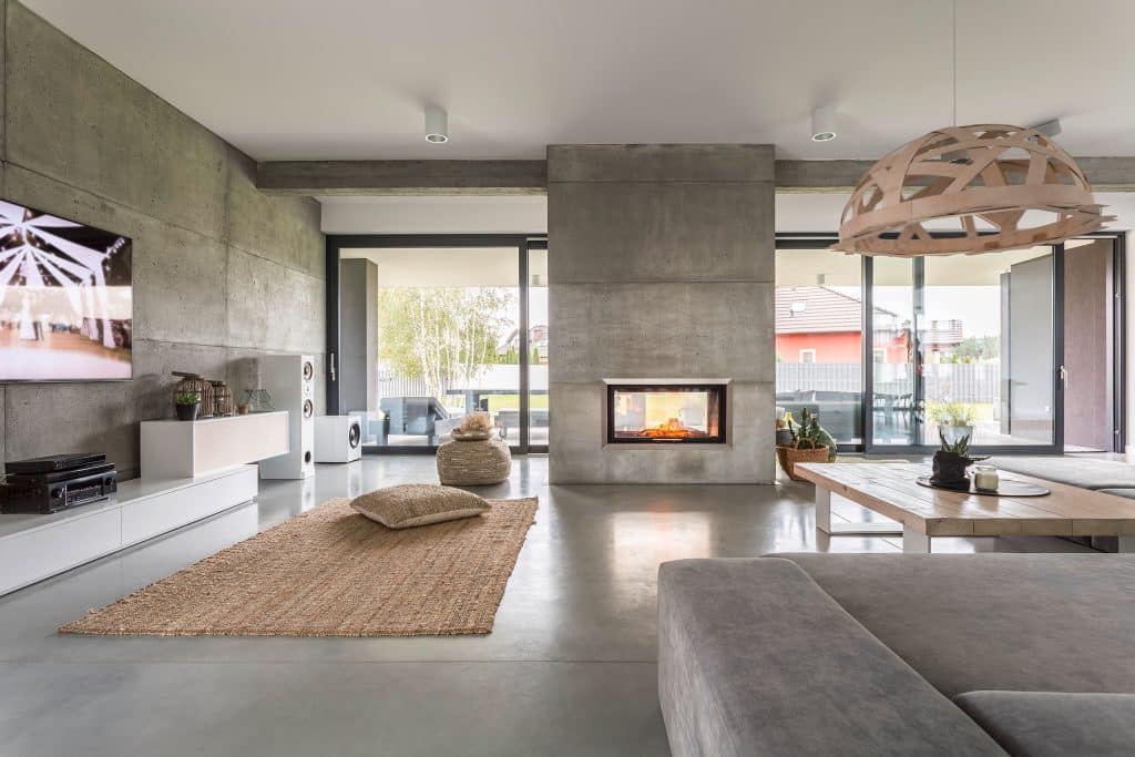 Großzügige, moderne Villa mit freistehendem Kamin im Betonlook im Wohnraum.