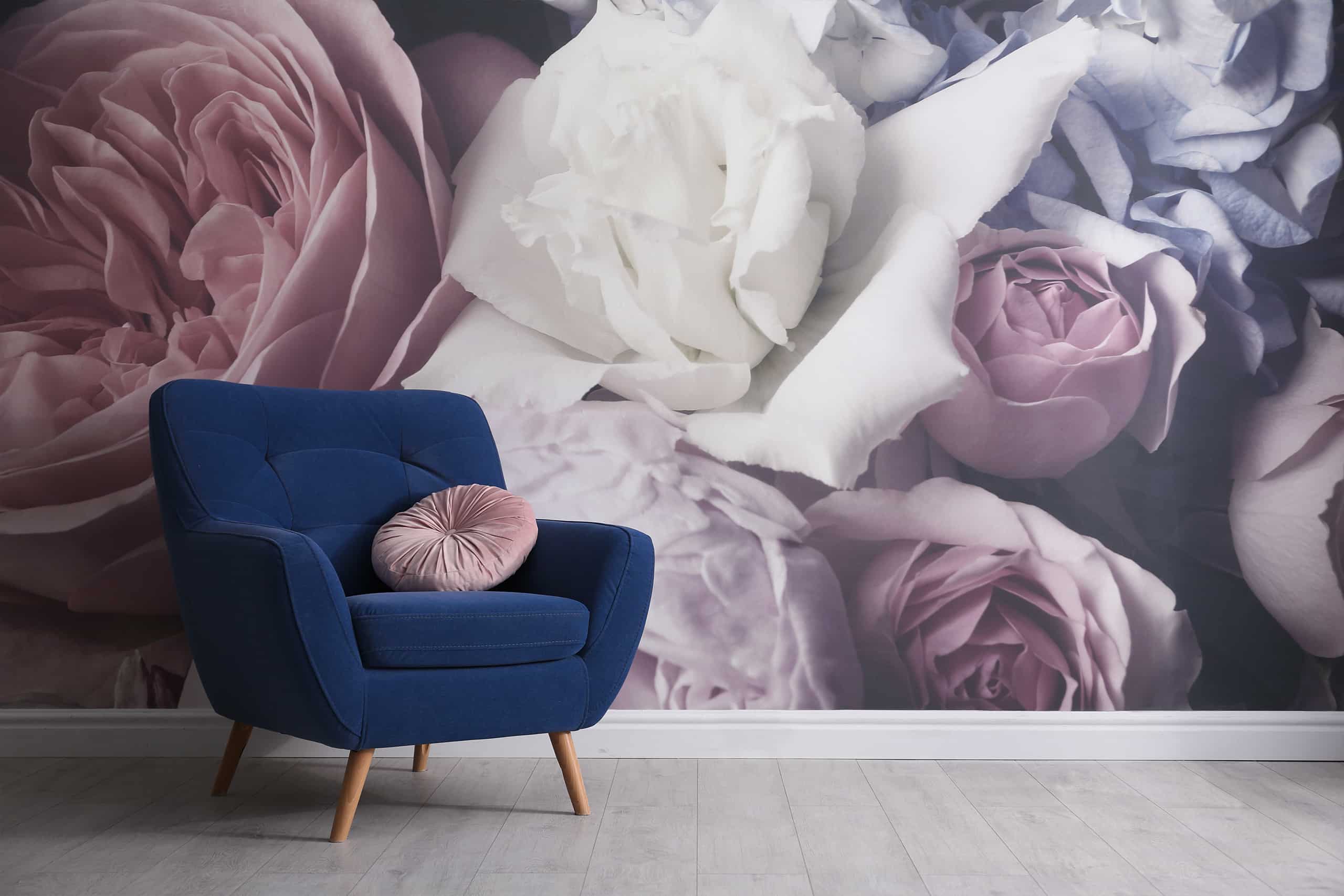 Bequemer Sessel in Royalblau vor einer Wand mit beeindruckender Blumentapete in Pastelltönen.