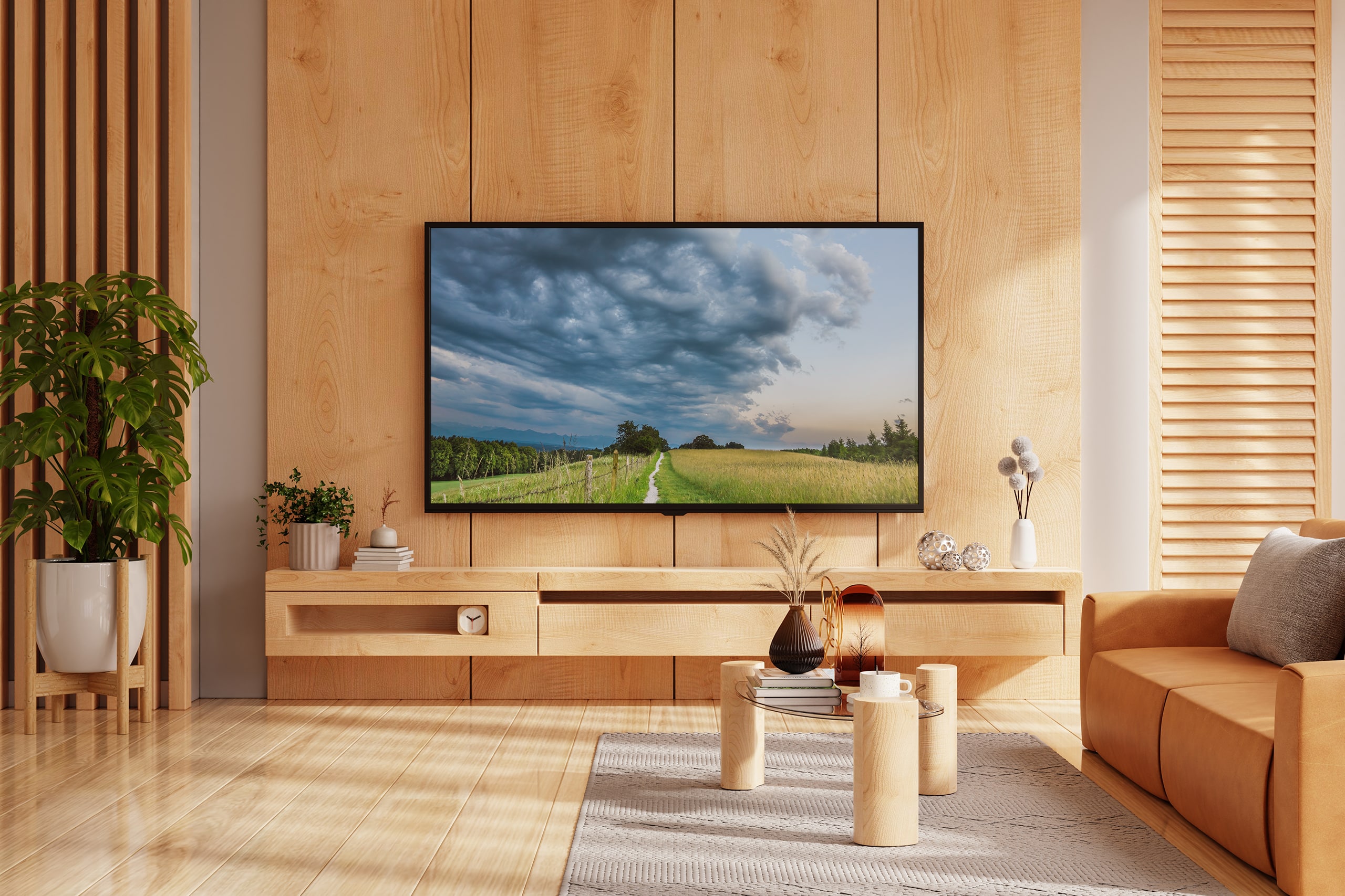 An der Wand montierter Fernseher über einem Lowboard aus hellem Holz im Wohnzimmer, mit Ledersofa und Deko-Accessoires; minimalistisches Design.