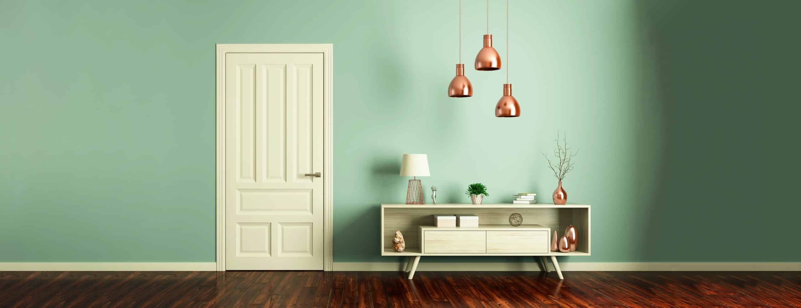 Weiße Innentür wird durch petrolfarbene Wand hervorgehoben und kleines Sideboard im Retro-Look mit Accessoires in Szene gesetzt.