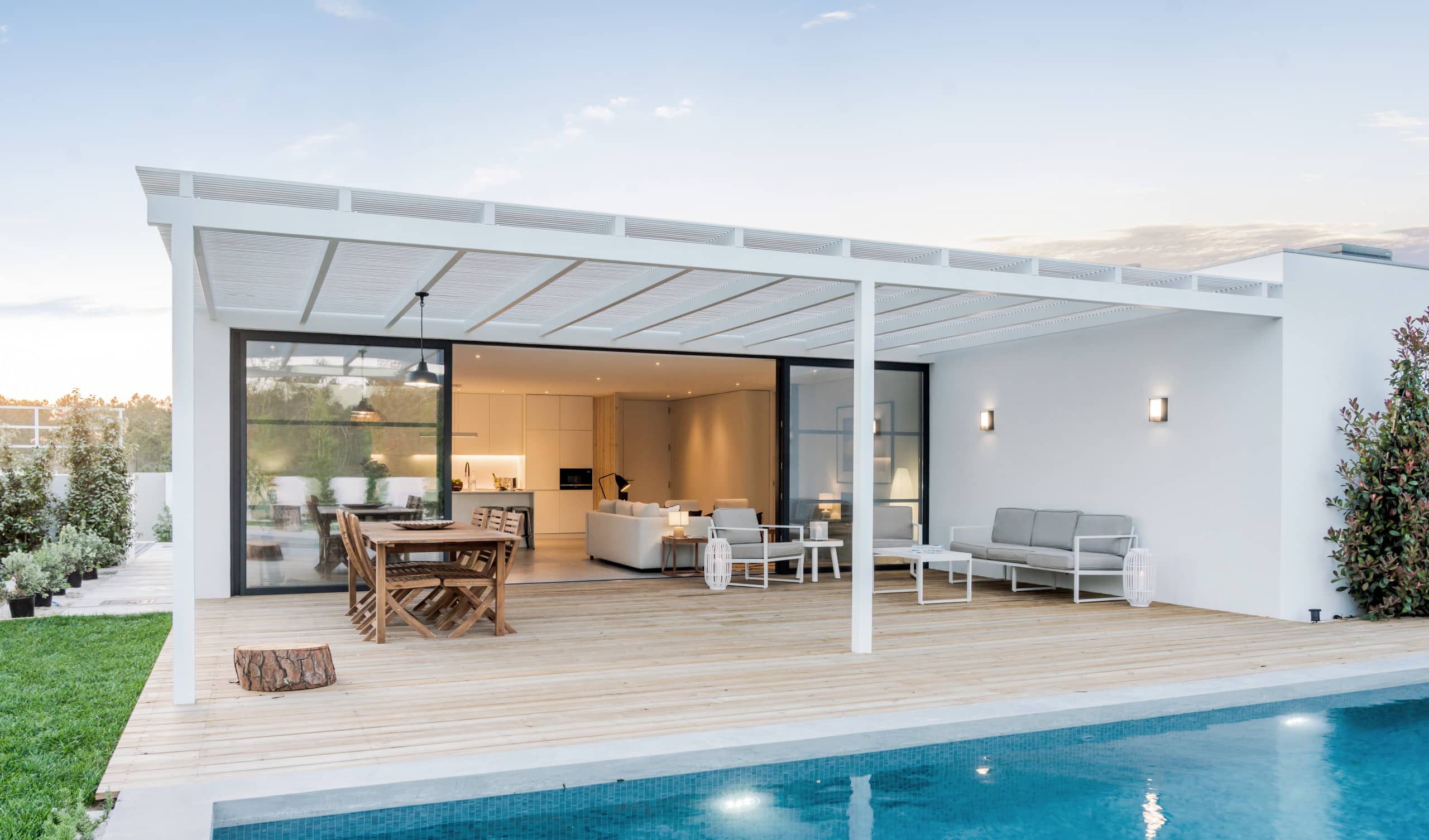 Überdachte Terrasse eine Bungalows mit schönem Pool in Abendstimmung.