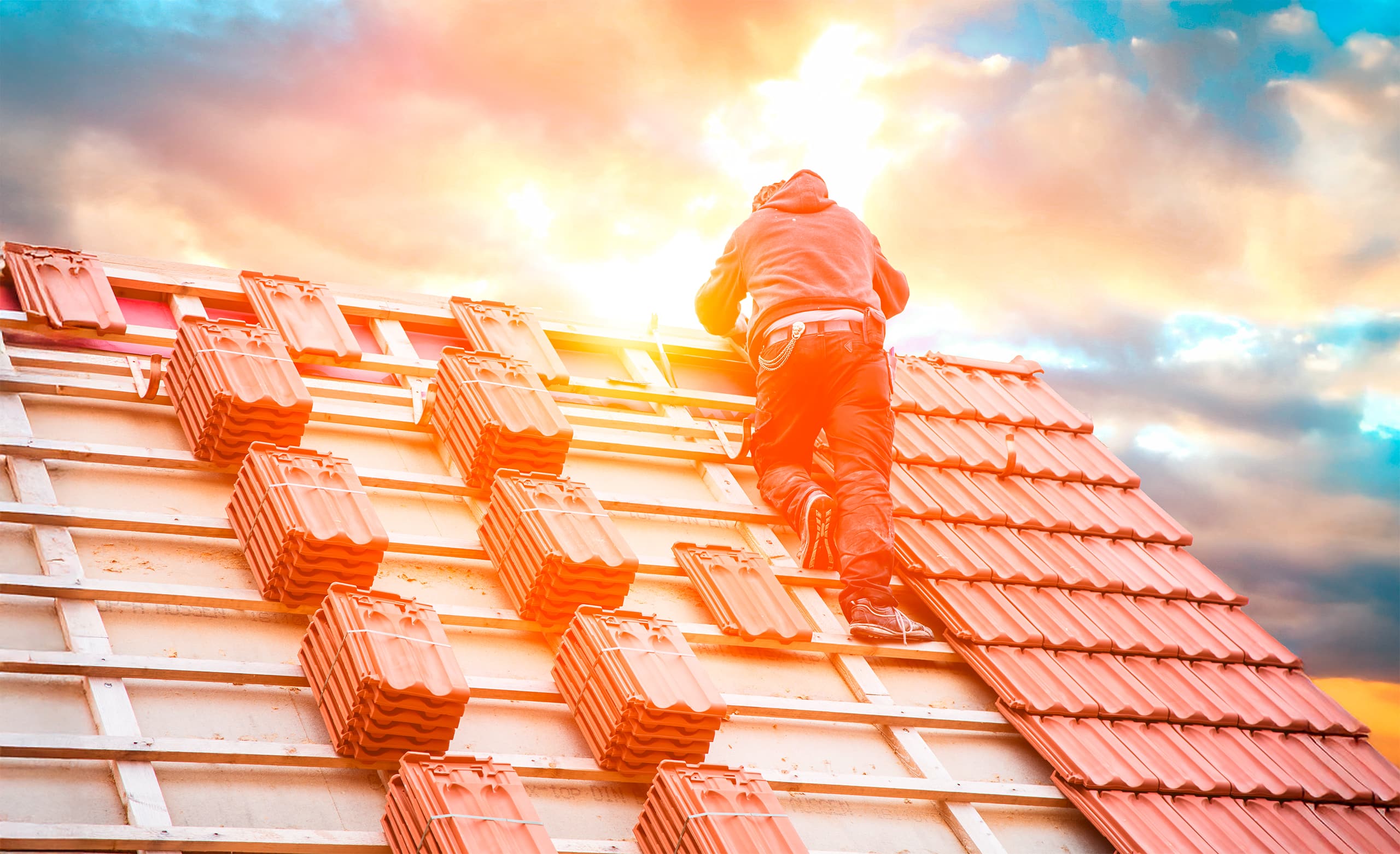 Dachdecker beim Decken eines neuen Daches mit gebrannten, roten Ziegeln.