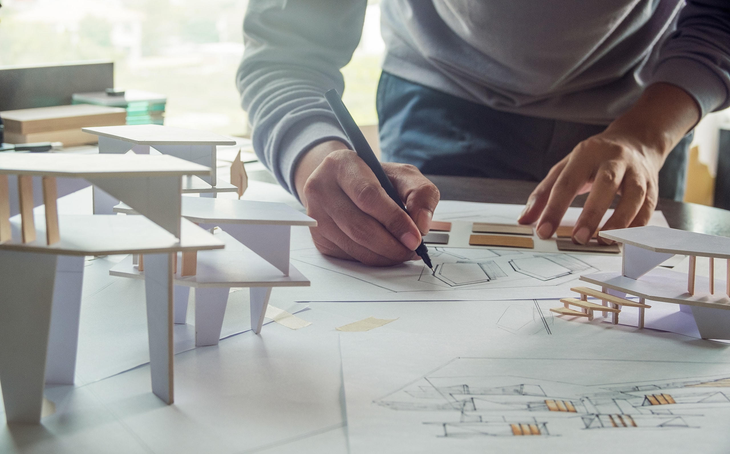 Architekt entwirft, zeichnet, skizziert und plant auf Blaupausen ein neues Gebäude Bund erstellt ein architektonisches Hausmodell.