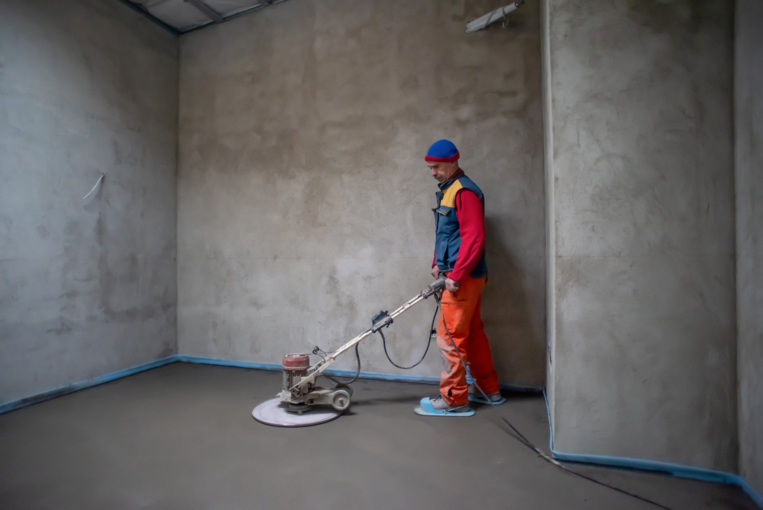 Arbeiter bei der Bearbeitung und beim maschinellen Glätten eines Sand-Zement-Estrichbodens.