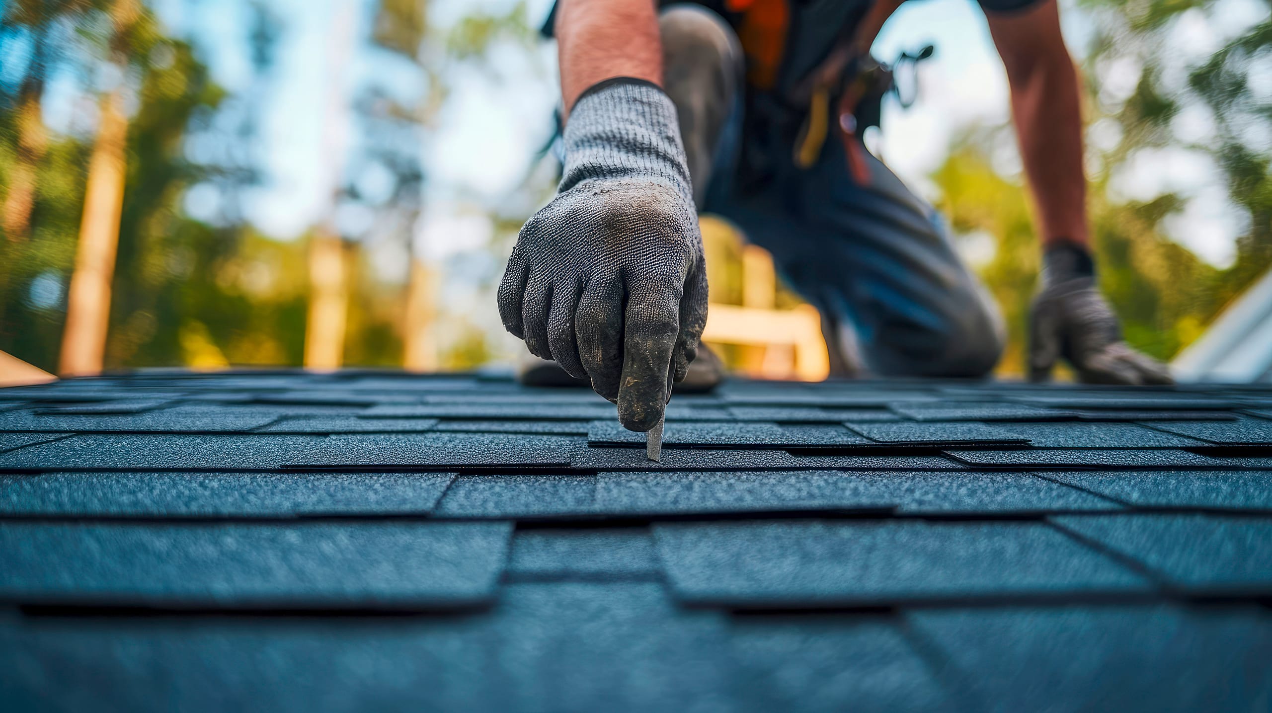 Dachdecker installieren Asphaltschindeln bzw. Bitumenschindeln auf dem Dach eines neuen Hauses.