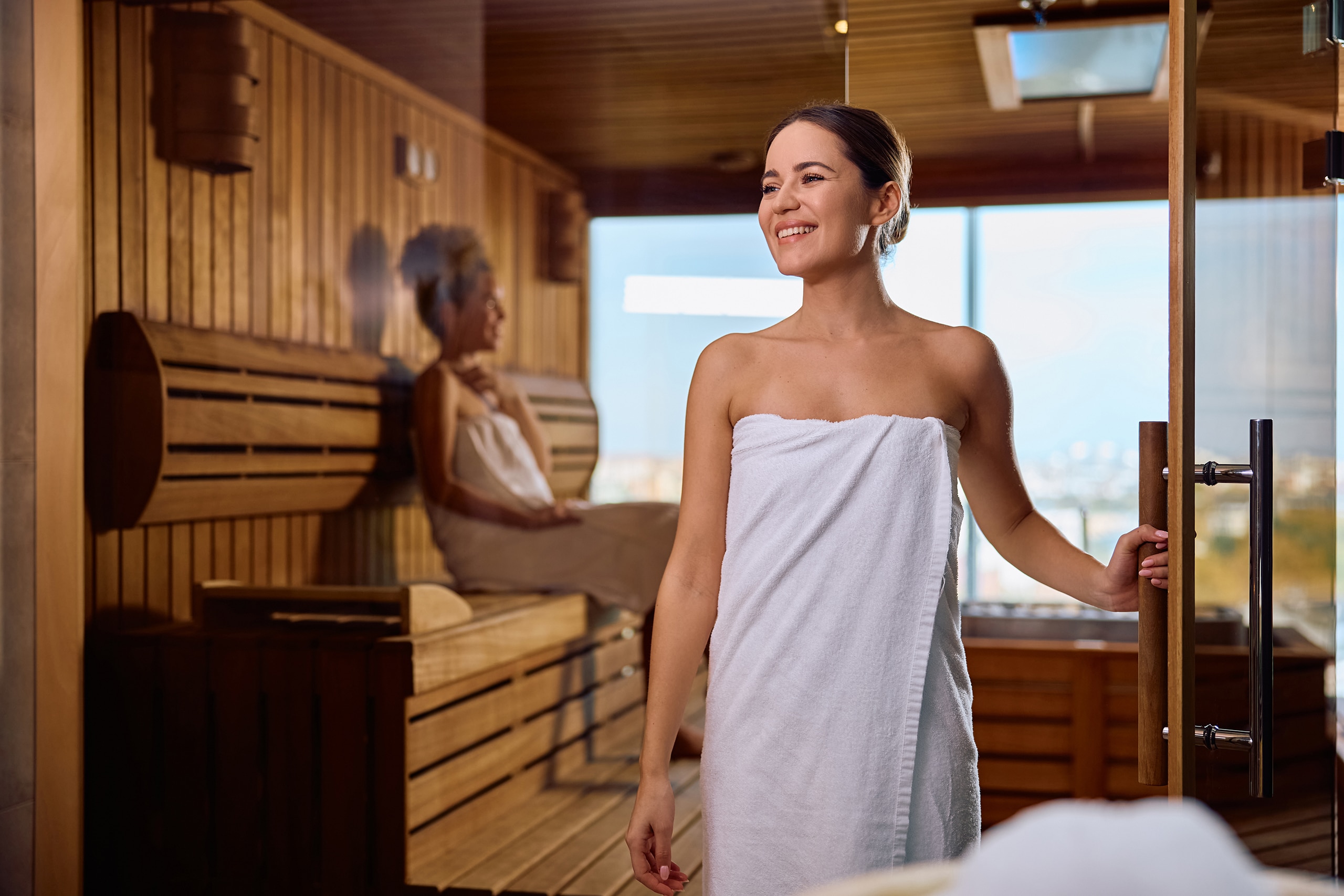 Junge Frau kommt gerade glücklich und entspannt aus der Sauna.