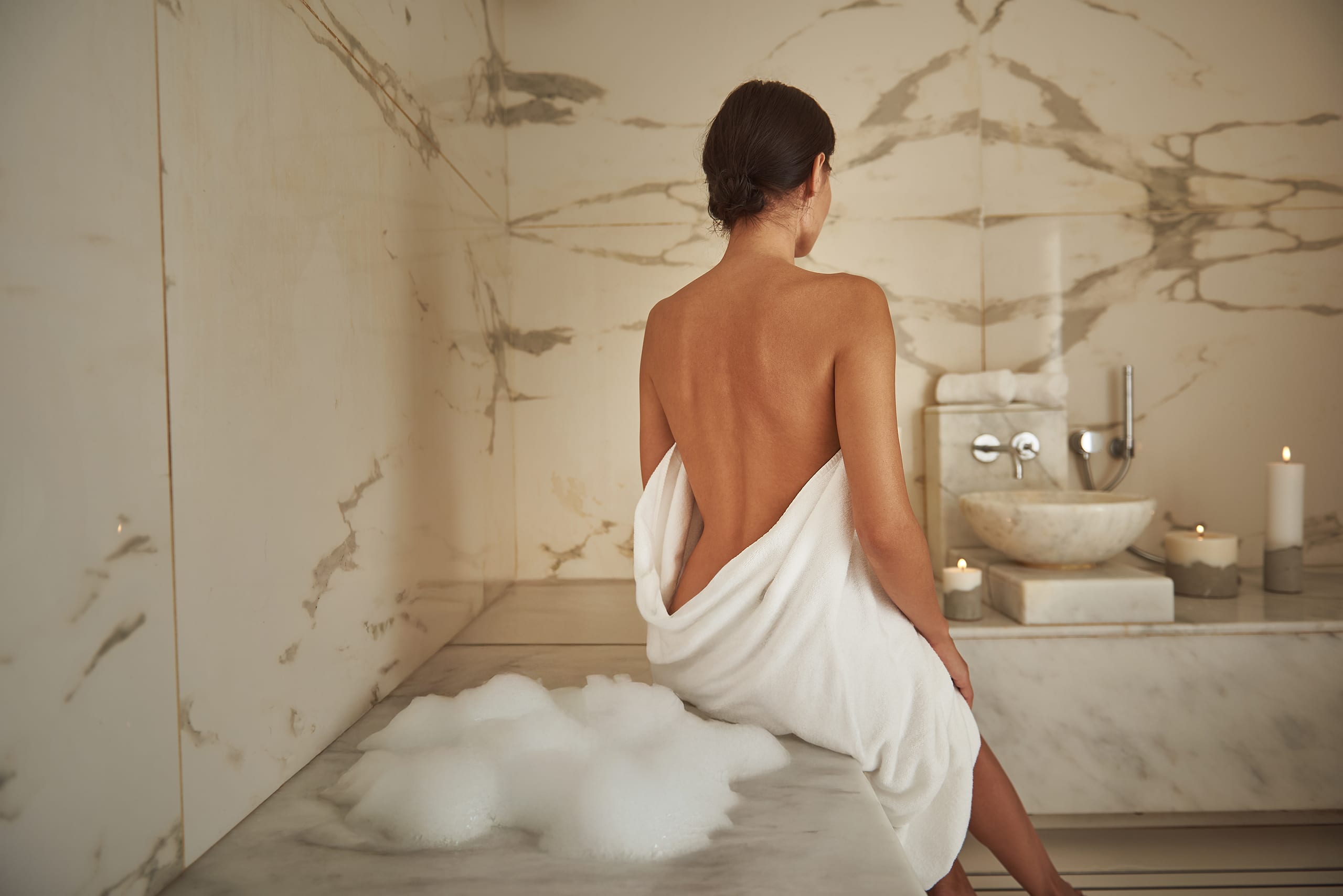 Junge Frau genießt die abgeschlossene Hamam-Anwendung in einem modernen SPA-Bereich.