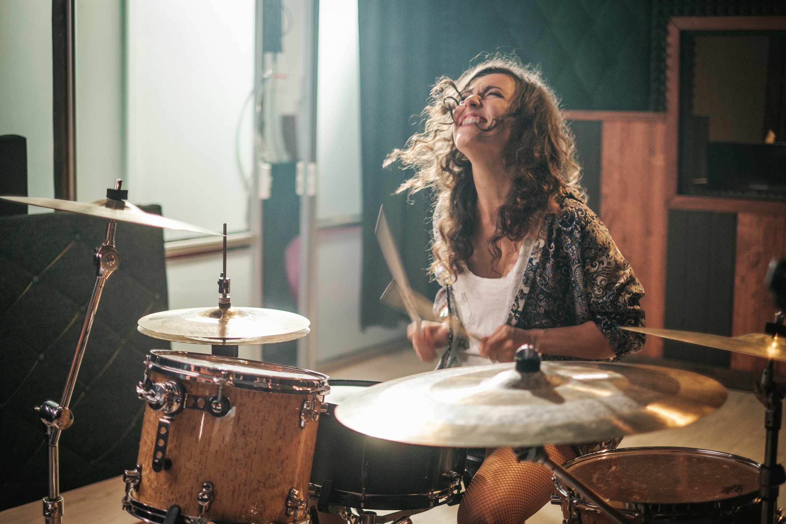 Junge Frau übt mit Begeisterung am Schlagzeug im der als Proberaum umgebauten GAaage.
