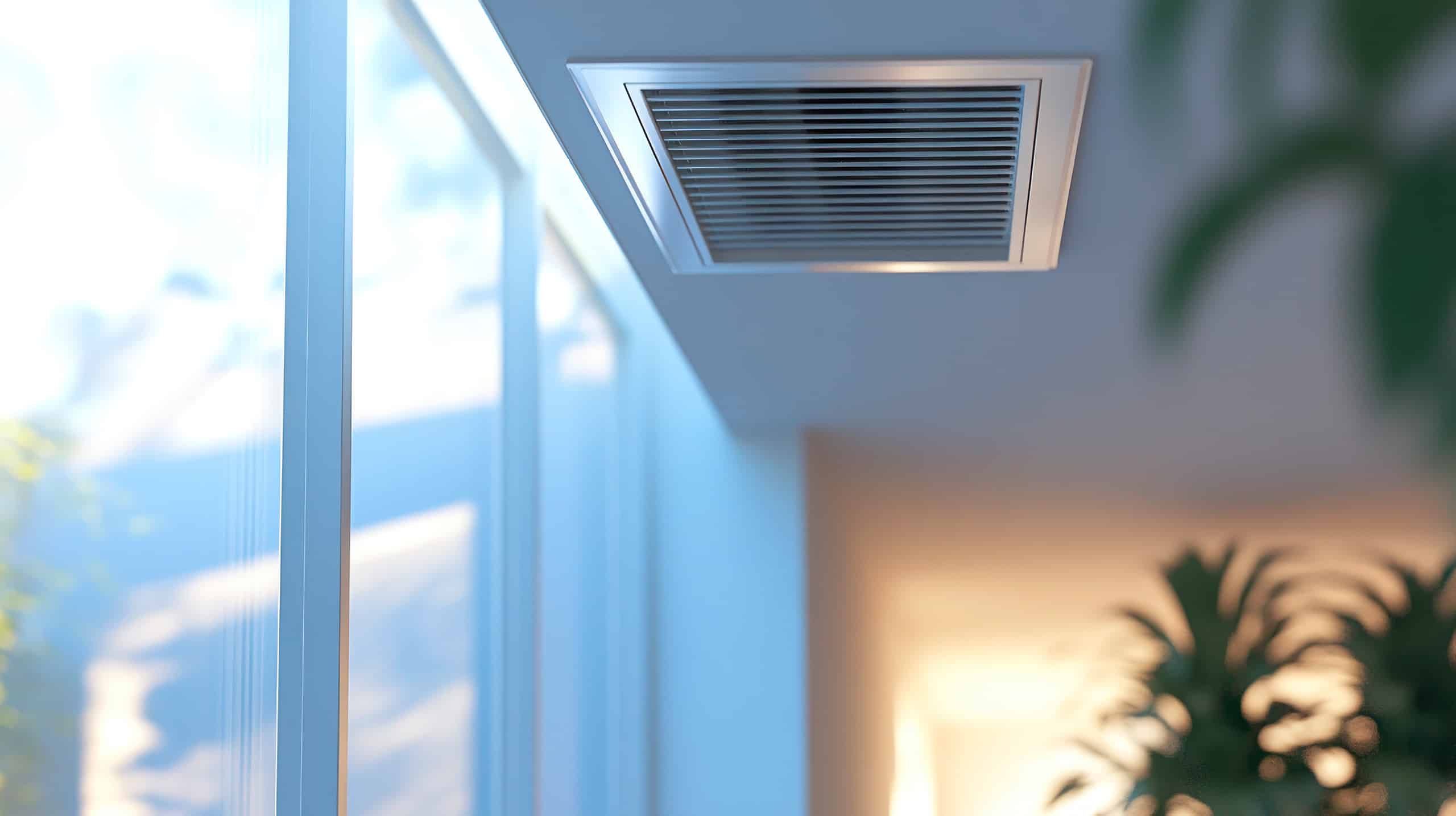 Detailansicht einer an der Decke installierten Wohnraumbelüftung nahe der großzügigen Fensterflächen eines modernen Wohnraumes.