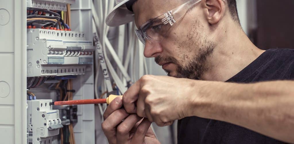 Elektriker schraubt im geöffneten Schaltkasten.