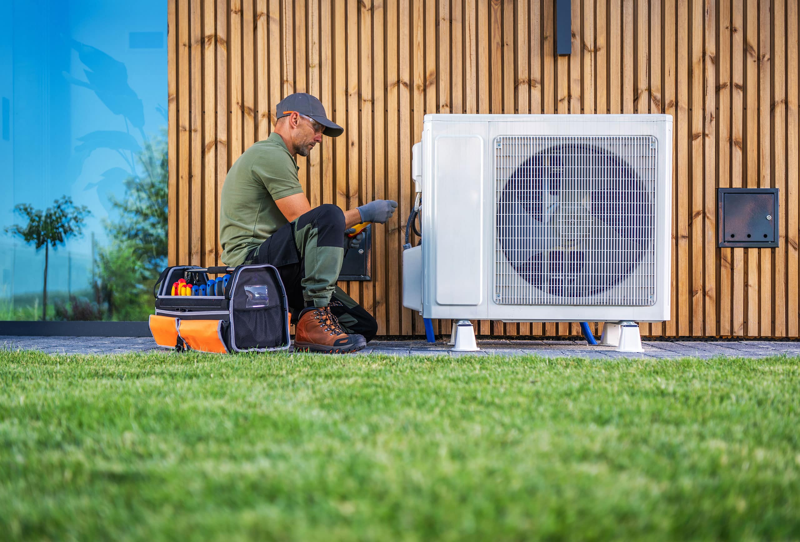 Techniker führt tagsüber Wartungsarbeiten an einer Klimaanlage im Außenbereich druch.